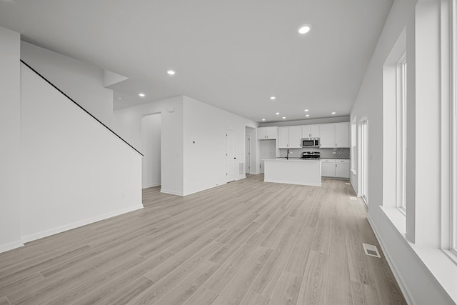 unfurnished living room with light wood finished floors, baseboards, visible vents, and recessed lighting