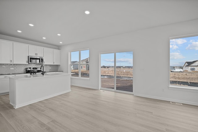 kitchen featuring tasteful backsplash, visible vents, appliances with stainless steel finishes, a sink, and light wood-type flooring