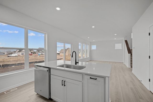 kitchen featuring a kitchen island with sink, a sink, visible vents, stainless steel dishwasher, and light wood-type flooring