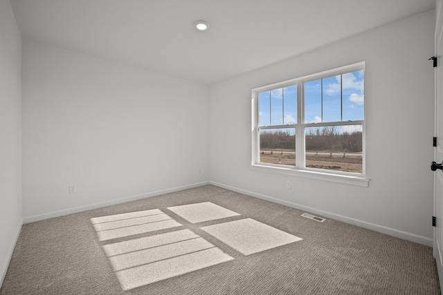 spare room with carpet, visible vents, and baseboards