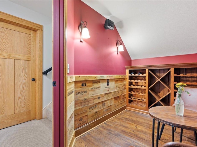 wine cellar featuring lofted ceiling, wood walls, and wood finished floors