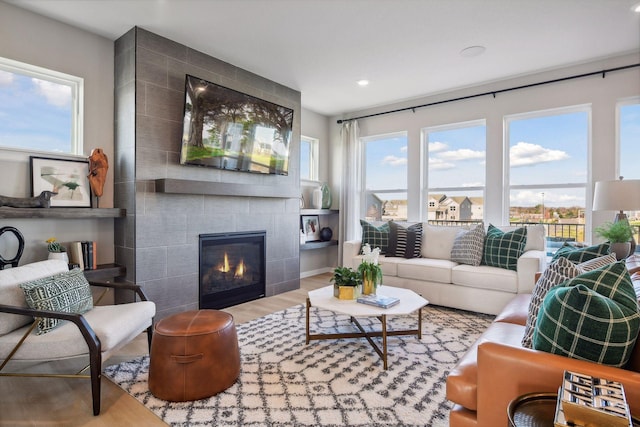 living room with a tile fireplace and light hardwood / wood-style floors