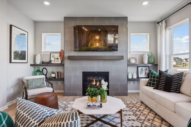 living room with a tiled fireplace and light hardwood / wood-style floors