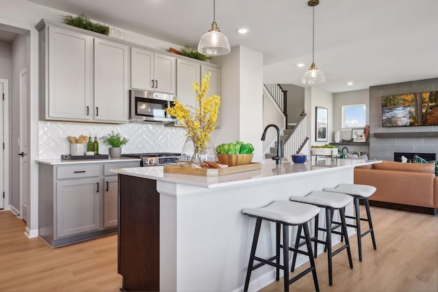 kitchen featuring decorative light fixtures, gray cabinets, and a kitchen island with sink