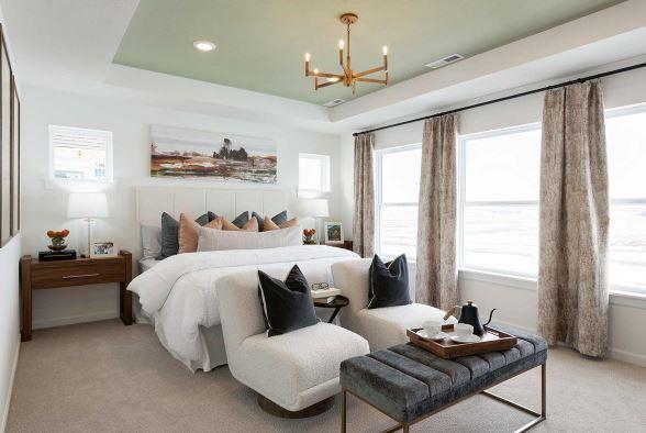 bedroom with a chandelier, light colored carpet, and a raised ceiling