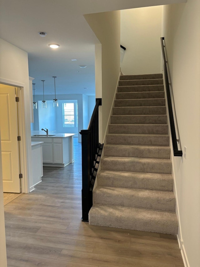 staircase featuring baseboards, wood finished floors, and recessed lighting