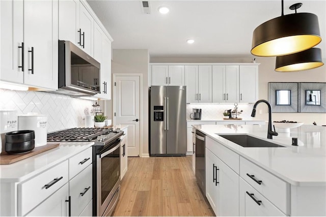 kitchen featuring appliances with stainless steel finishes, white cabinets, light countertops, and a sink