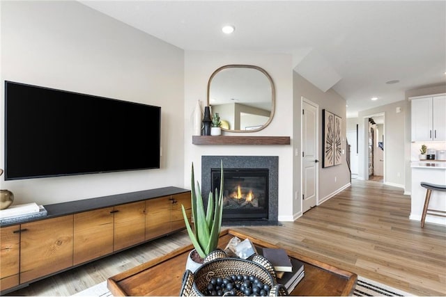 living room with a fireplace with flush hearth, recessed lighting, light wood-style flooring, and baseboards