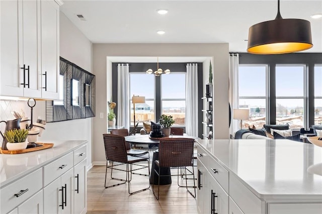 kitchen featuring white cabinets, light wood-style floors, pendant lighting, and light countertops