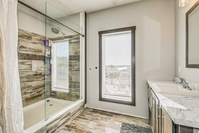 bathroom with tiled shower, vanity, and wood-type flooring