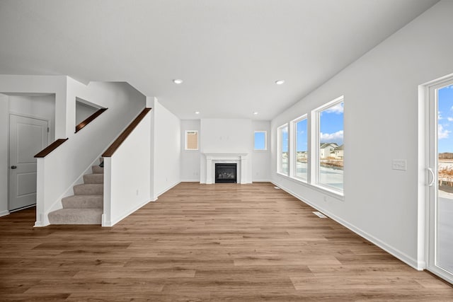 unfurnished living room with recessed lighting, a fireplace, stairway, and light wood finished floors