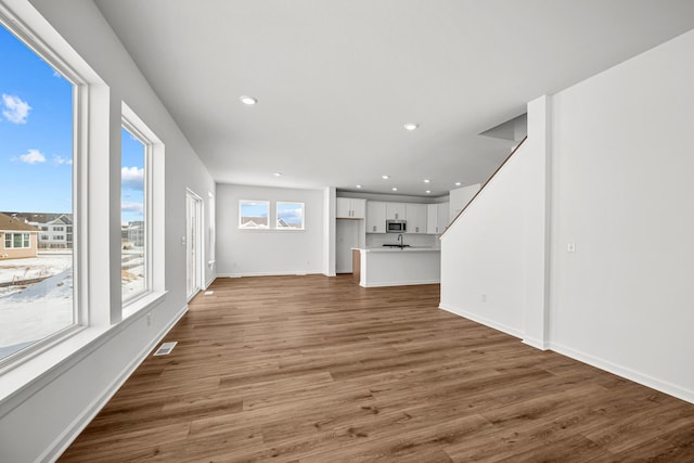 unfurnished living room featuring baseboards, visible vents, wood finished floors, and recessed lighting