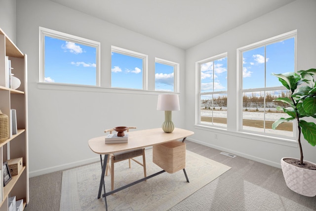 office space with plenty of natural light, visible vents, and light colored carpet