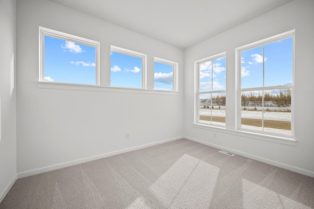 empty room featuring carpet floors, visible vents, and baseboards