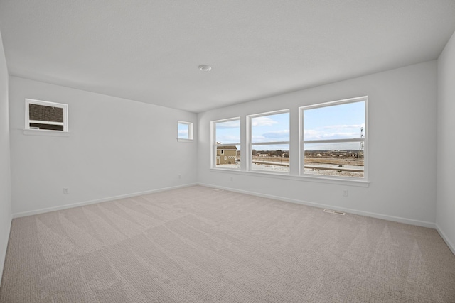 empty room featuring visible vents, baseboards, and light colored carpet