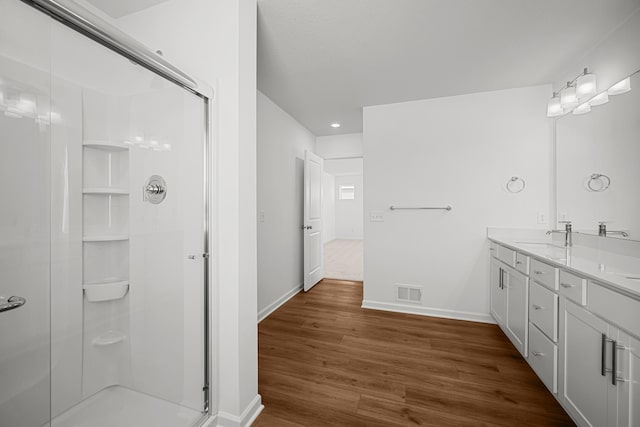 bathroom featuring double vanity, baseboards, visible vents, wood finished floors, and a shower stall