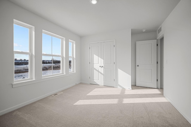 unfurnished bedroom featuring light carpet, visible vents, baseboards, and a closet