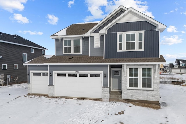 view of front of home with a garage, stone siding, a shingled roof, and board and batten siding