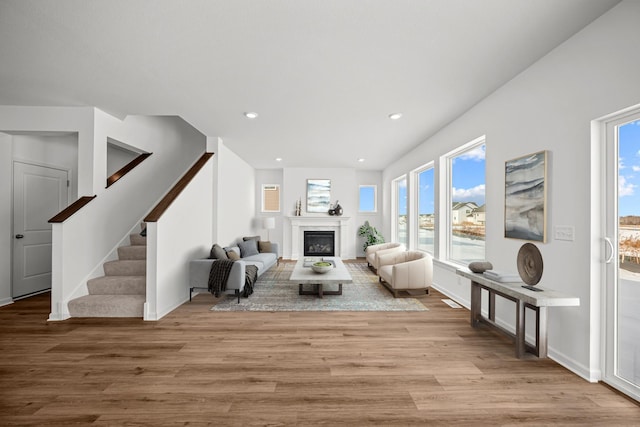 living area featuring recessed lighting, stairs, wood finished floors, and a glass covered fireplace