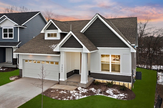 view of front of house featuring a garage, a yard, and central air condition unit