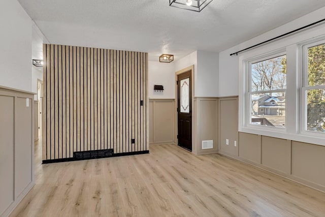 unfurnished living room with a textured ceiling and light hardwood / wood-style flooring