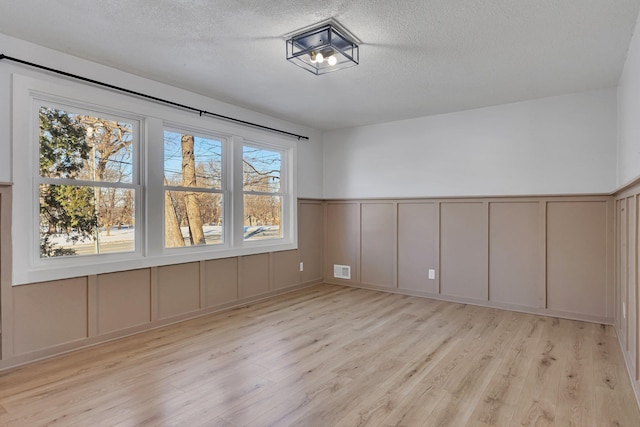 empty room with light hardwood / wood-style floors and a textured ceiling