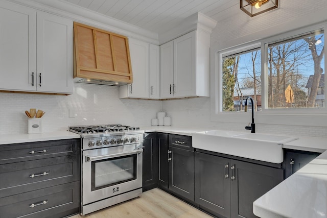 kitchen featuring white cabinetry, sink, high end stainless steel range oven, crown molding, and light hardwood / wood-style flooring