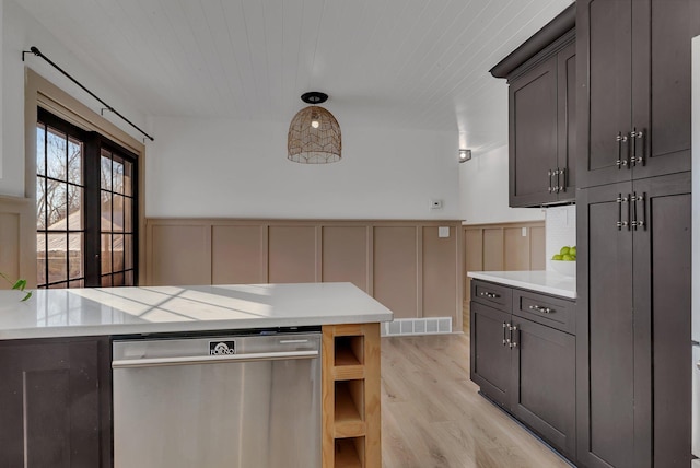 kitchen with hanging light fixtures, dark brown cabinets, stainless steel dishwasher, and light hardwood / wood-style floors