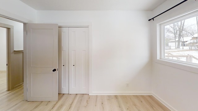 unfurnished bedroom with a closet and light wood-type flooring