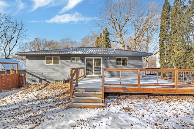 snow covered back of property with a deck