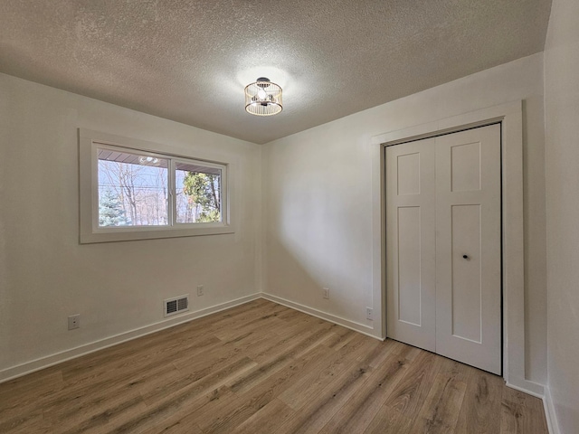 spare room featuring light hardwood / wood-style flooring and a textured ceiling