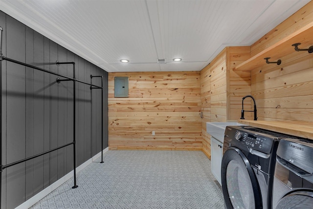 laundry area featuring washer / dryer, sink, electric panel, and wood walls