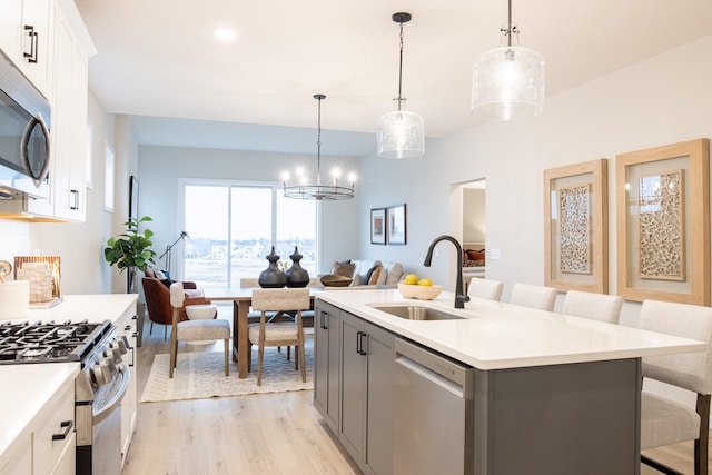 kitchen featuring a breakfast bar, light wood finished floors, stainless steel appliances, light countertops, and a sink