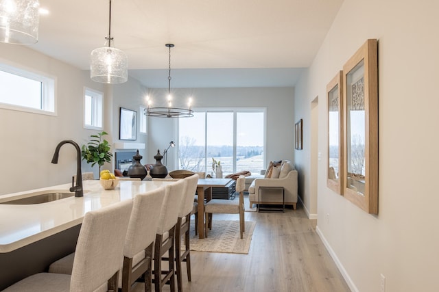 dining space featuring light wood-style floors, a notable chandelier, and baseboards