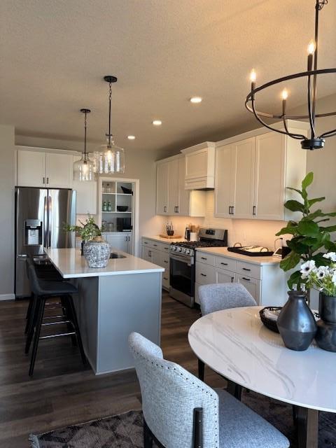 kitchen featuring light countertops, appliances with stainless steel finishes, an island with sink, and white cabinets