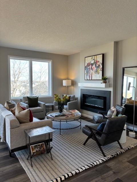 living room featuring a glass covered fireplace, a healthy amount of sunlight, and wood finished floors