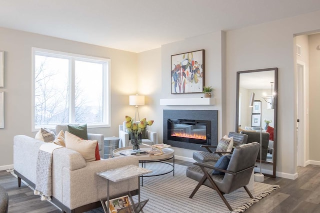 living room featuring dark wood-style floors, baseboards, and a glass covered fireplace