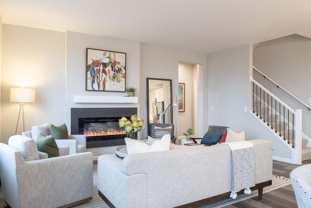 living area with stairway, dark wood-type flooring, and a glass covered fireplace