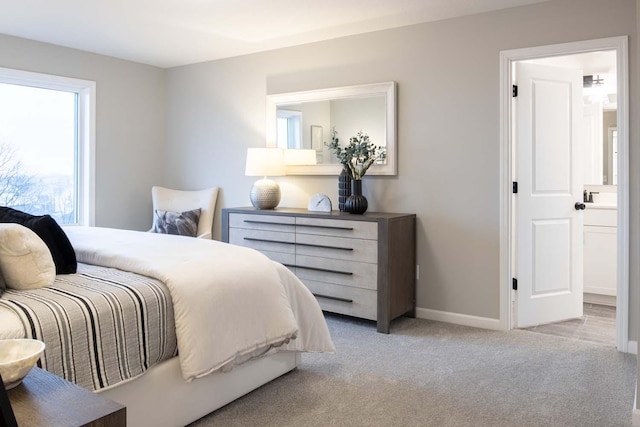 bedroom with light carpet, a sink, and baseboards