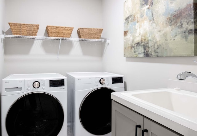 laundry area with cabinet space, a sink, and washer and clothes dryer