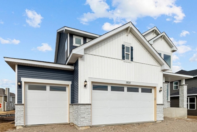 view of front of property with an attached garage, stone siding, and board and batten siding