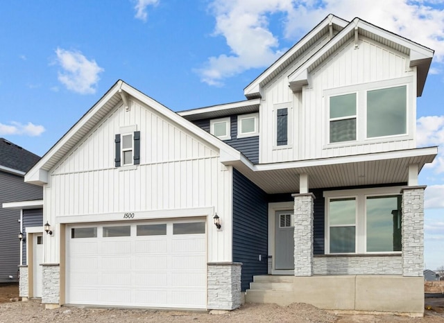 modern farmhouse style home featuring board and batten siding, stone siding, covered porch, and a garage