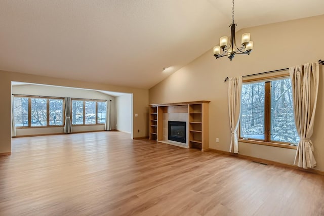 unfurnished living room with an inviting chandelier, lofted ceiling, a tile fireplace, and light wood-type flooring