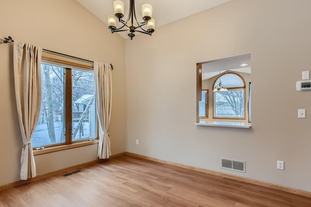 empty room featuring lofted ceiling, light hardwood / wood-style flooring, and a chandelier