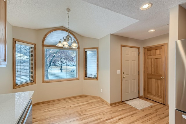 interior space with baseboards, a textured ceiling, a chandelier, and light wood-style flooring