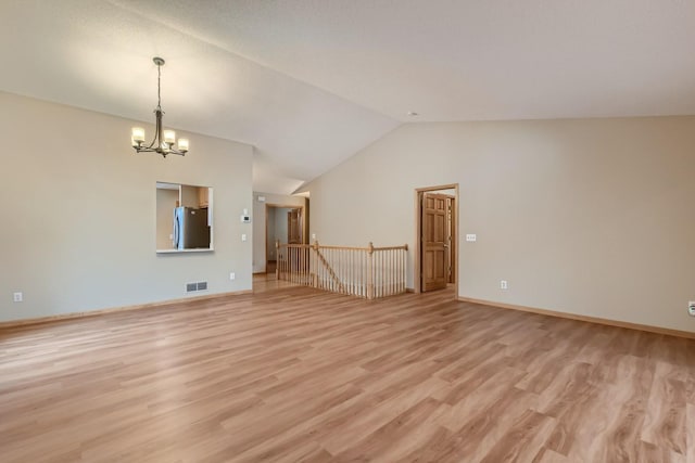 unfurnished room with visible vents, baseboards, lofted ceiling, an inviting chandelier, and light wood-style flooring