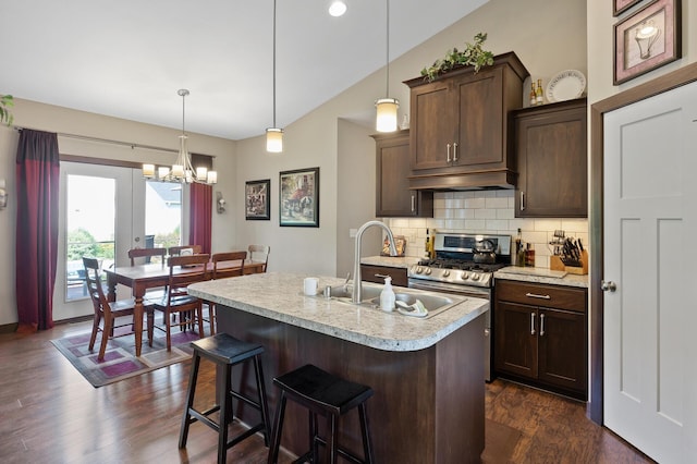 kitchen with light countertops, backsplash, gas stove, a sink, and under cabinet range hood