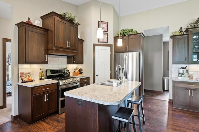 kitchen with decorative backsplash, dark wood-style flooring, stainless steel appliances, light countertops, and a sink