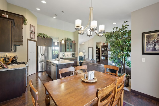 dining space with dark wood-style flooring, recessed lighting, a high ceiling, an inviting chandelier, and baseboards