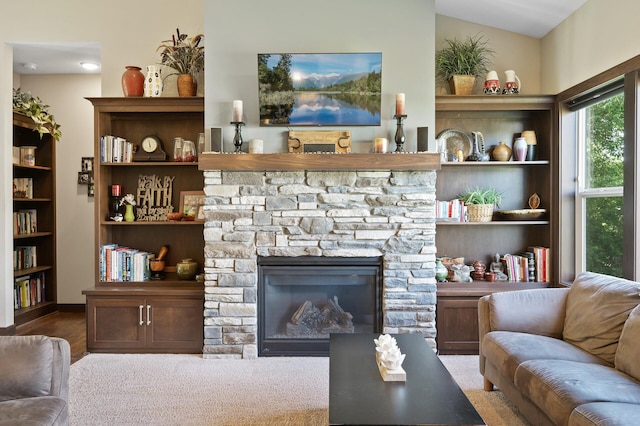 living room with built in features, vaulted ceiling, and a fireplace